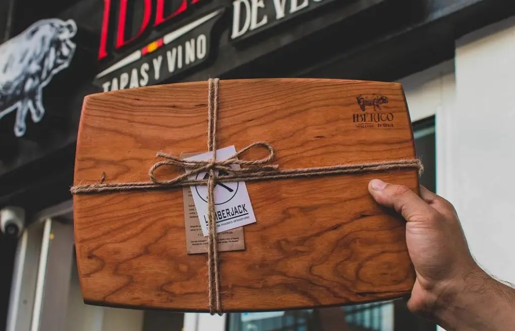 Tabla cherry de servicio con logo de toro y marca grabada — pieza de madera grabada para Ibérico Tapas y Vino · De Vega